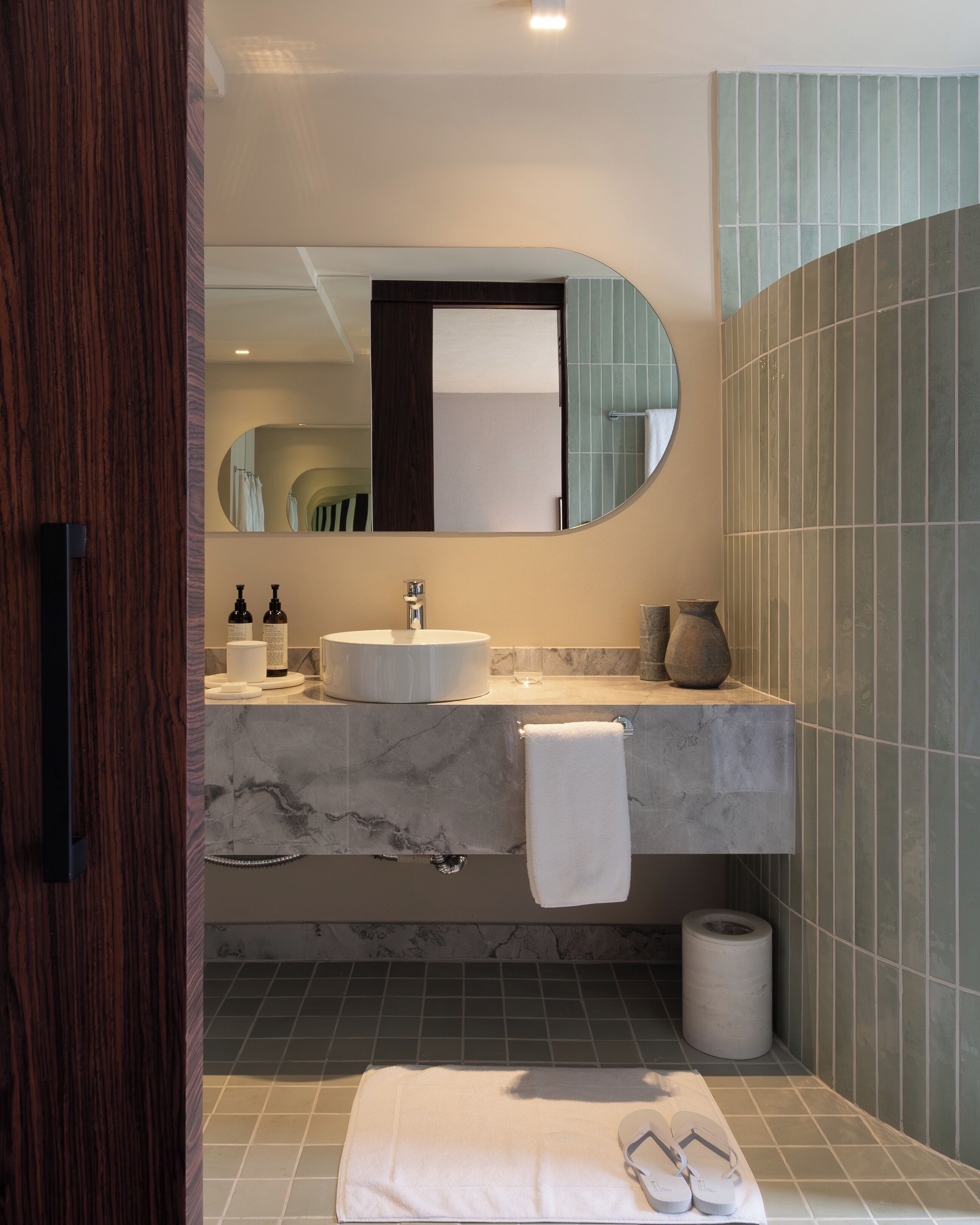 Un baño moderno con lavabo de mármol, un espejo grande y un perchero para toallas.