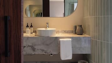Un baño moderno con lavabo de mármol, un espejo grande y un perchero para toallas.