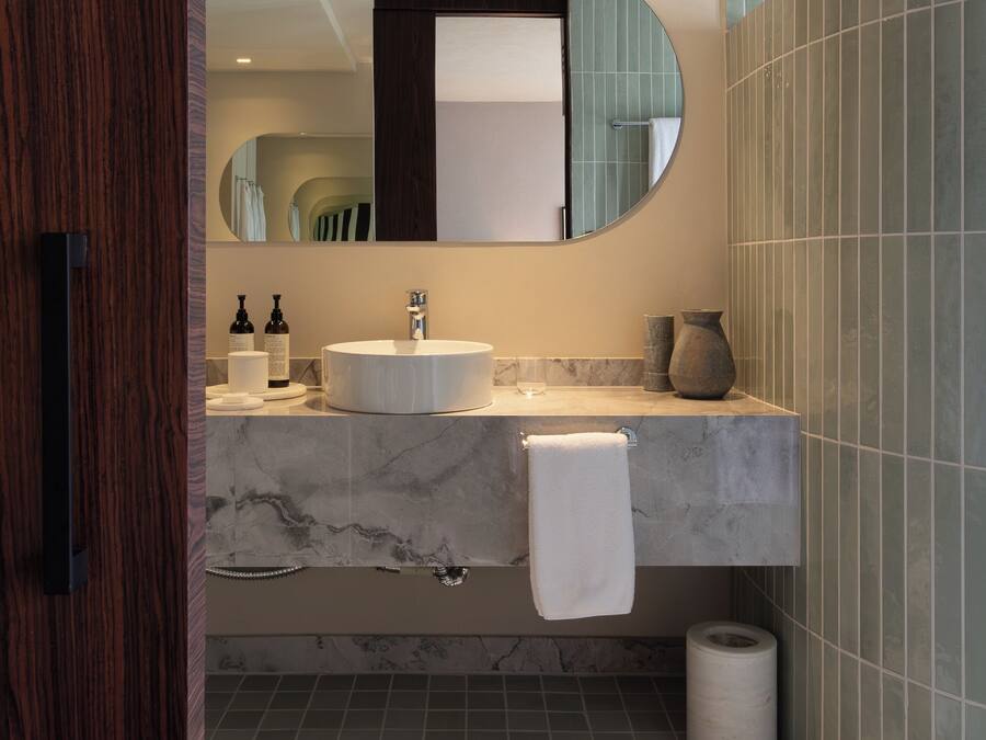 Un baño moderno con lavabo de mármol, un espejo grande y un perchero para toallas.