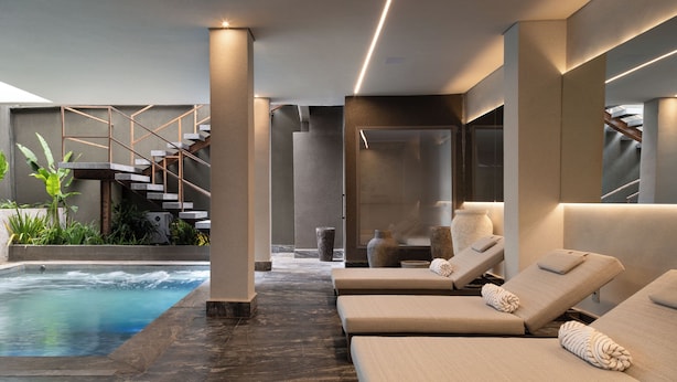 A modern indoor pool area with lounge chairs and a staircase. - Íz Hotel Conceito (Goiânia)