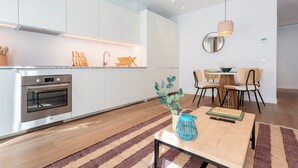 A modern kitchen with white cabinets, a built-in oven, and a dining area with a wooden table and chairs. - Genteel Home Zabaleta III (Madrid)