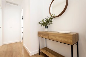 A hallway with a wooden console table, a potted plant, and a round mirror on the wall.