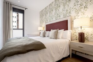 A hotel room with a bed, nightstands, a lamp, and a window with curtains.