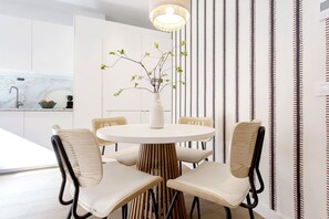 A modern dining area with a round table, four chairs, and a vase with branches.