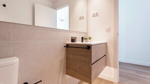 A modern bathroom with a toilet, a wooden vanity with a sink, and a mirror above the vanity.