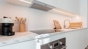 A modern kitchen with a built-in espresso machine, a coffee maker, a knife block, and a sink.