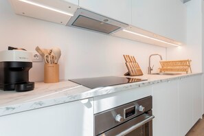 Une cuisine moderne équipée d’une machine à expresso intégrée, d’une cafetière, d’un bloc à couteaux et d’un évier.