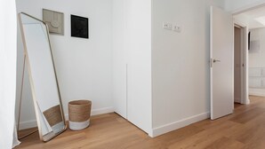 Een gang met een grote spiegel, een mand en een deur naar een andere kamer.