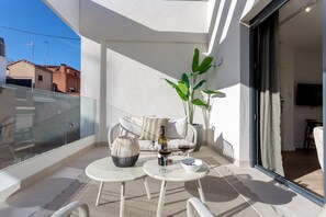 A balcony with a table, chairs, a sofa, a plant, and a wine bottle. - Genteel Home Zabaleta Terrace VI (Madrid)