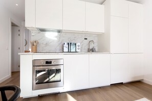 A modern kitchen with white cabinetry, a built-in oven, a marble backsplash, and a stainless steel faucet. - Genteel Home Zabaleta Terrace VI (Madrid)