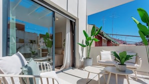 En balkon med siddeplads, inklusive en sofa og stole, samt et bord med en potteplante.