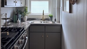 Una cocina funcional con estufa a gas, pileta doble y un candelabro decorativo.