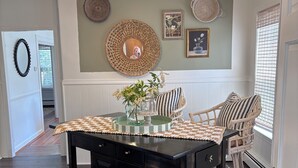Un comedor con una mesa de madera oscura, un posavasos tejido y un espejo decorativo en la pared.