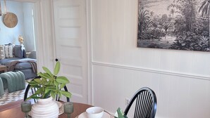 Un comedor con una mesa redonda, sillas, una araña de techo, un cuadro en la pared y una planta en maceta.