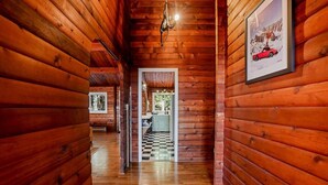 A wooden cabin interior with a checkered floor, a chandelier, and a framed picture on the wall. - Iconic Chalet: Sauna • Hot Tub • Fire Pit • Plunge (Shannondale)