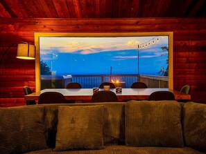 Un coin repas accueillant avec une table et des chaises, une vue sur un balcon doté d’une balustrade, et un intérieur chaleureux aux murs en bois.