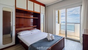 A bedroom with a bed, a wardrobe, a mirror, and a balcony with a view. - Your Stay by the Seaside in the Best Location of BC - Cets (Balneário Camboriú)