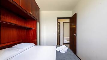 A hotel room with a bed, a small table, and a wooden wardrobe.