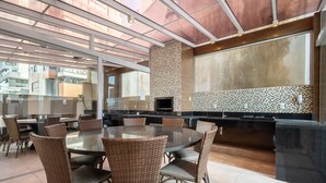 An outdoor dining area with a round table and wicker chairs, a tiled backsplash, and a modern design. - Your Stay by the Seaside in the Best Location of BC - Cets (Balneário Camboriú)