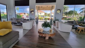 A spacious living area with a sofa, coffee table, and potted plants.