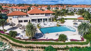 A resort with a swimming pool, lounge chairs, and palm trees.