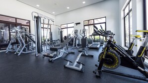 A modern gym with various exercise equipment, large windows, and a clean, spacious layout.