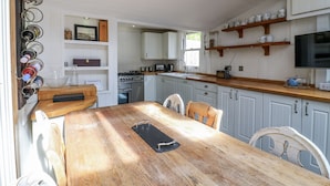 Una cocina con armarios blancos, una encimera de madera y una mesa de comedor con sillas.