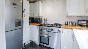 Una cocina moderna con electrodomésticos de acero inoxidable, armarios blancos y encimera de madera.