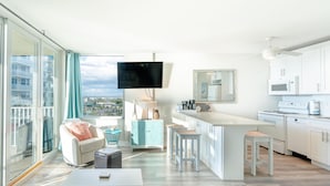 A modern apartment with a large living area, kitchen, and a balcony with a city view.