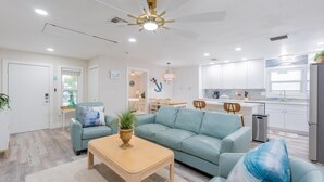 Un salon moderne avec un canapé bleu clair, une table basse en bois et un ventilateur de plafond.