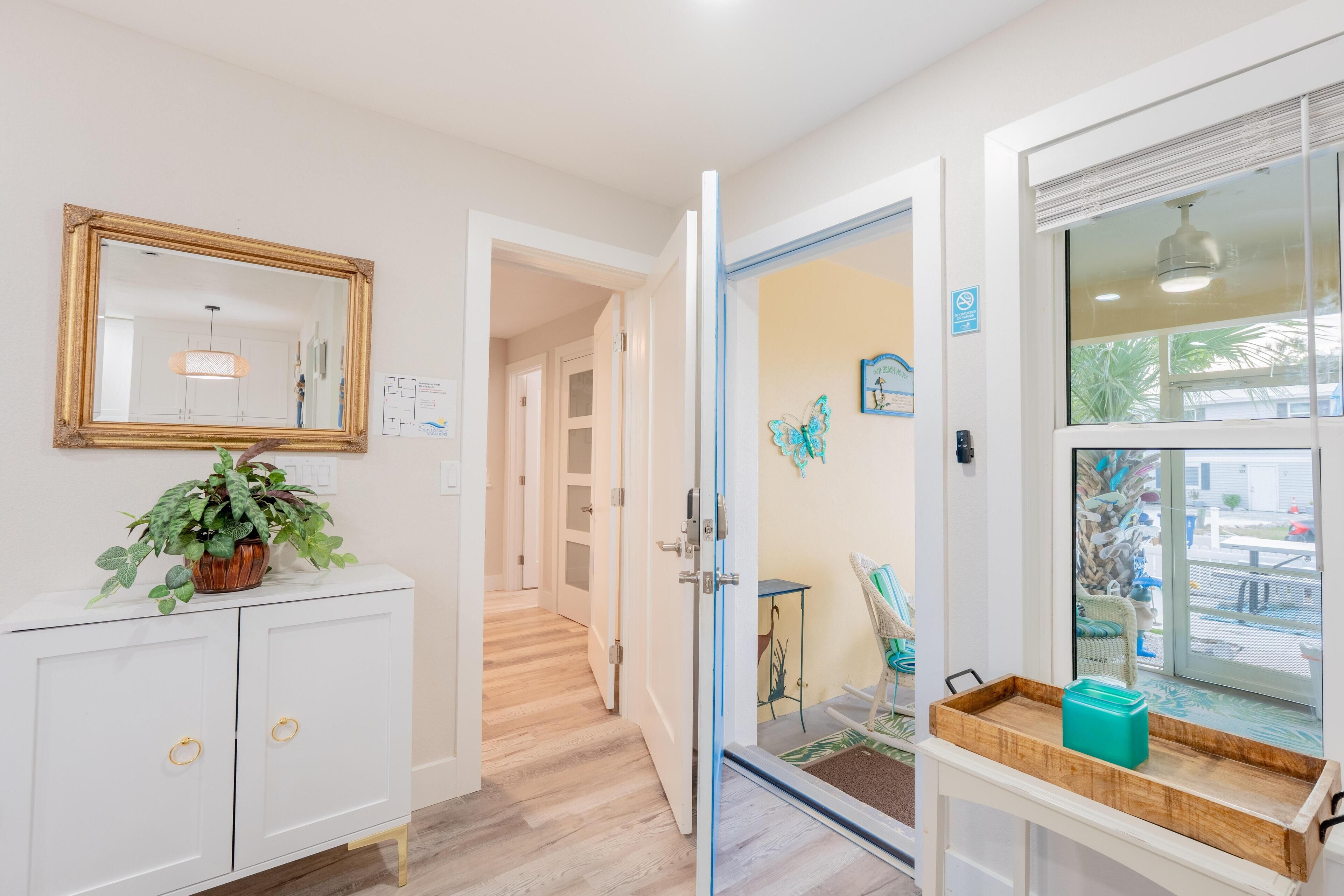 A hallway with a white cabinet, a mirror, and a potted plant.