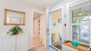 Un couloir avec une armoire blanche, un miroir et une plante en pot.