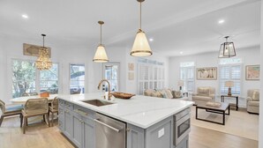 Une cuisine spacieuse dotée d’un grand îlot central, d’appareils électroménagers modernes et de luminaires suspendus.