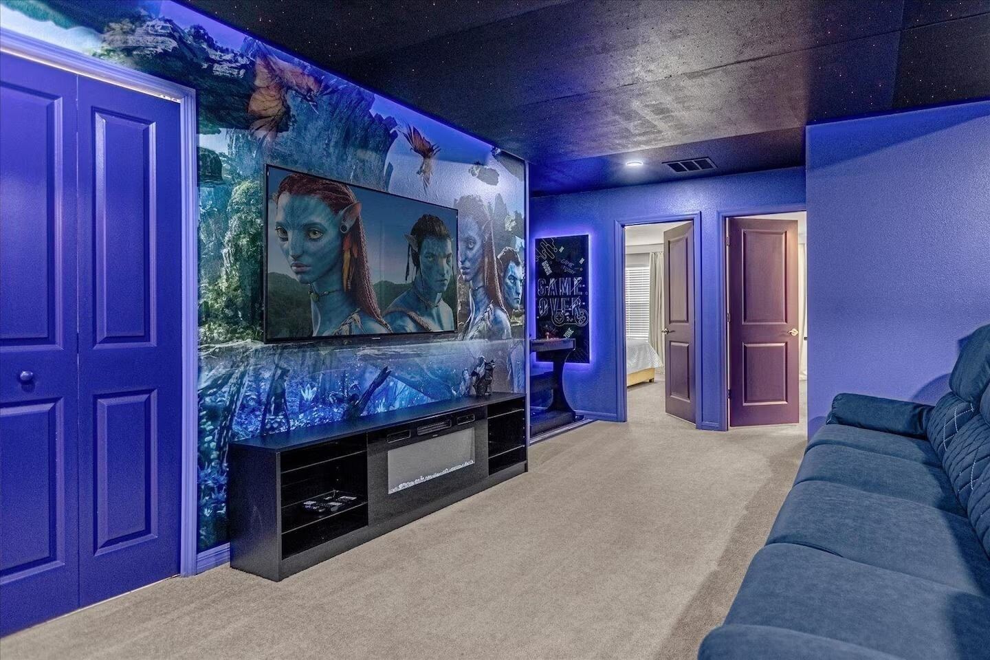 Ein Wohnzimmer mit einem großen Flachbildfernseher, einem blauen Sofa und einer Wandmalerei.