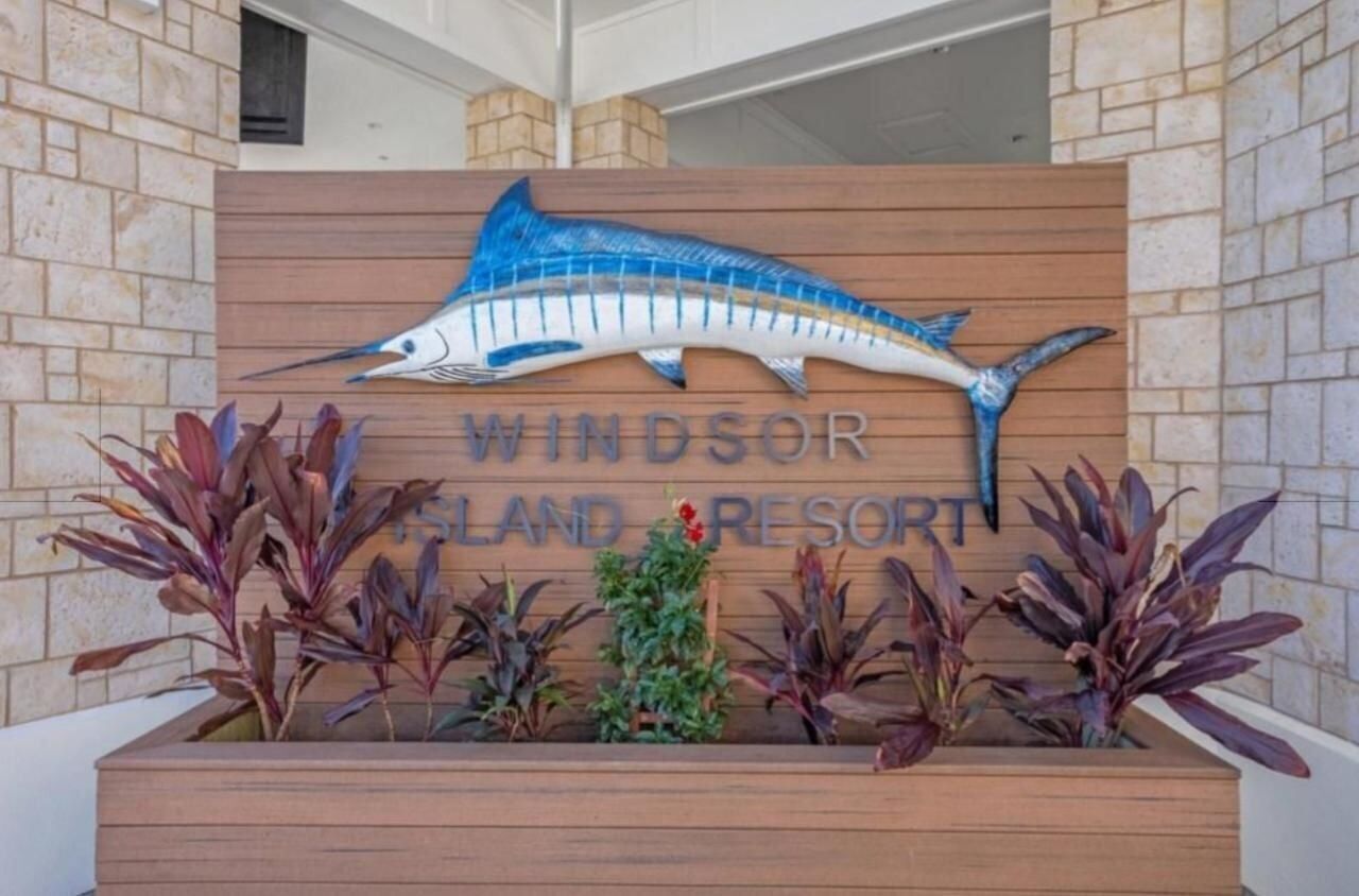 Une enseigne pour le complexe hôtelier Windsor Island Resort, avec un grand motif de poisson bleu et le nom du complexe.