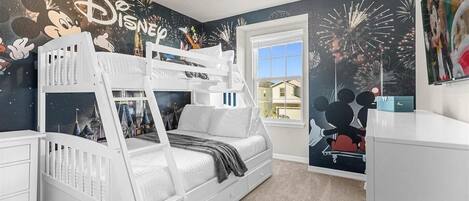 A child's bedroom with a bunk bed, Disney-themed wallpaper, and a window with a view of houses.