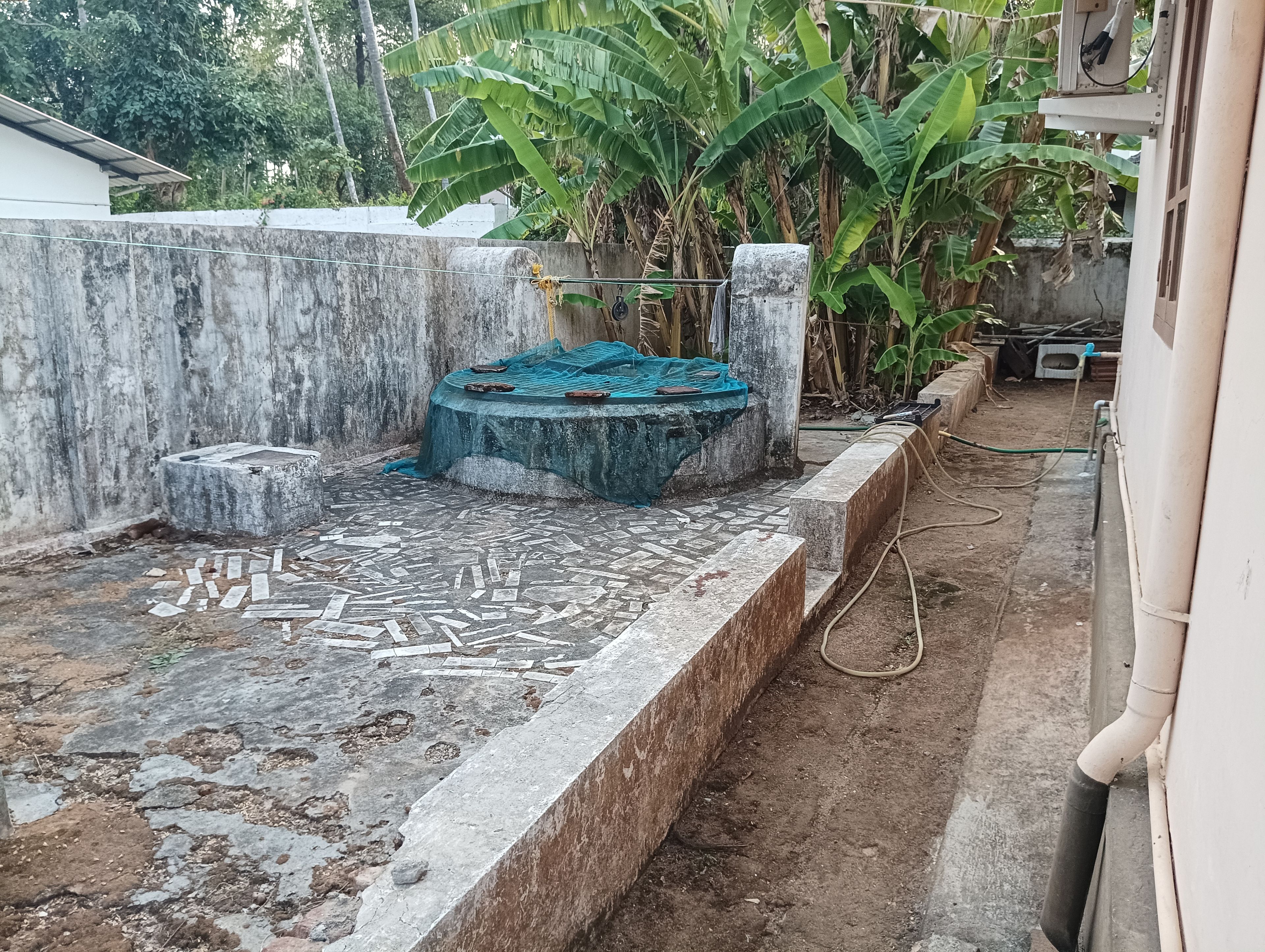 Une cour avec un sol carrelé, un banc en béton et un élément décoratif aquatique.