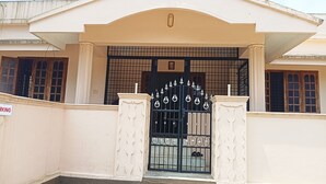 A building entrance with a black gate, white pillars, and a sign indicating a parking area.