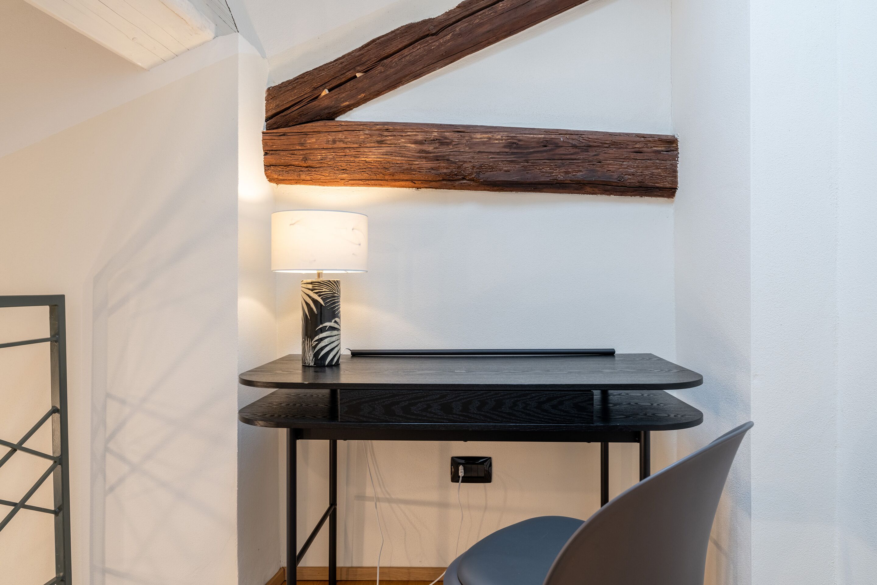 Une petite pièce moderne, avec une table en bois foncé, une lampe et une chaise.