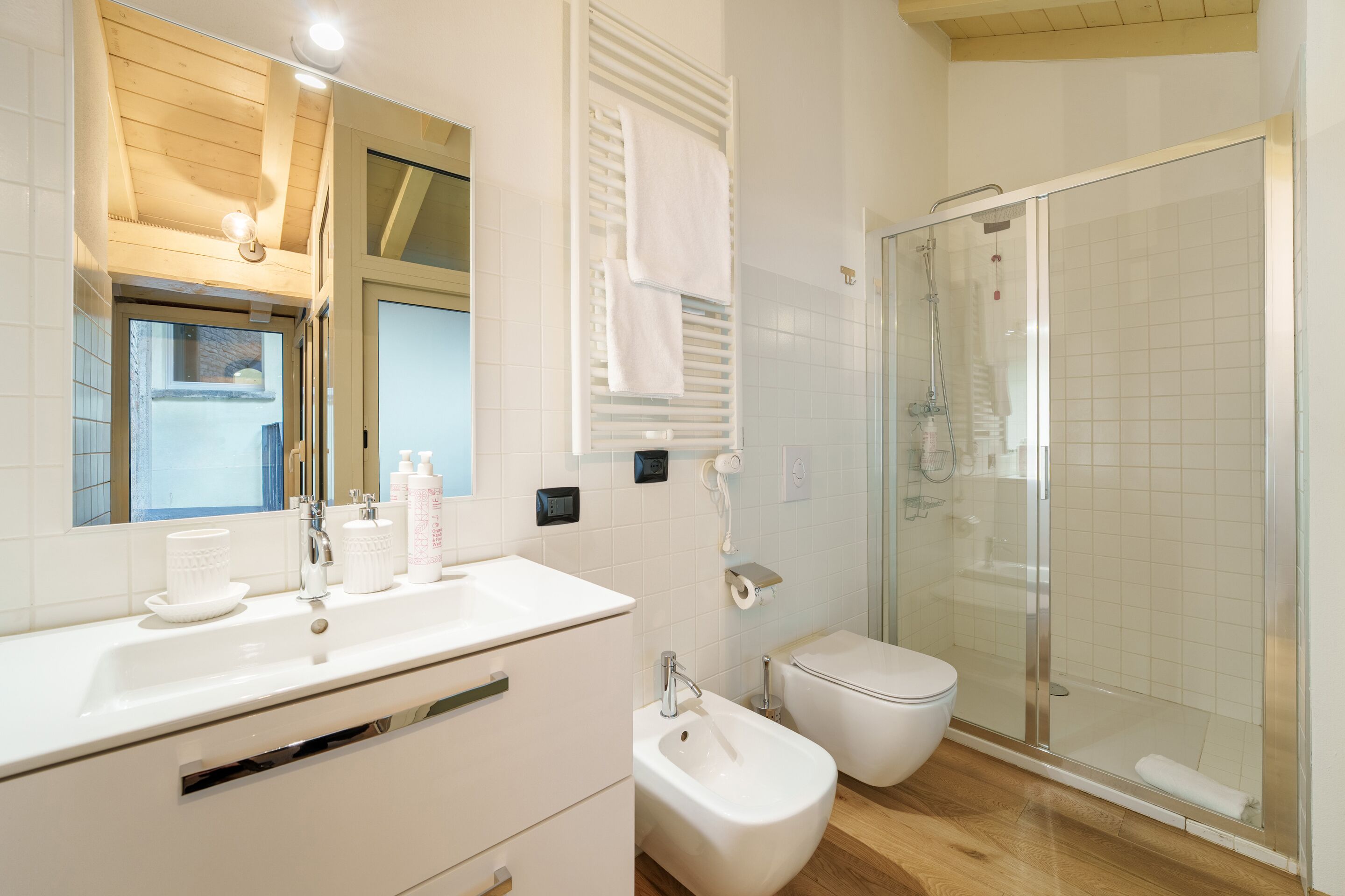 Un bagno moderno con un mobile lavabo bianco, uno spazio doccia in vetro e un water.