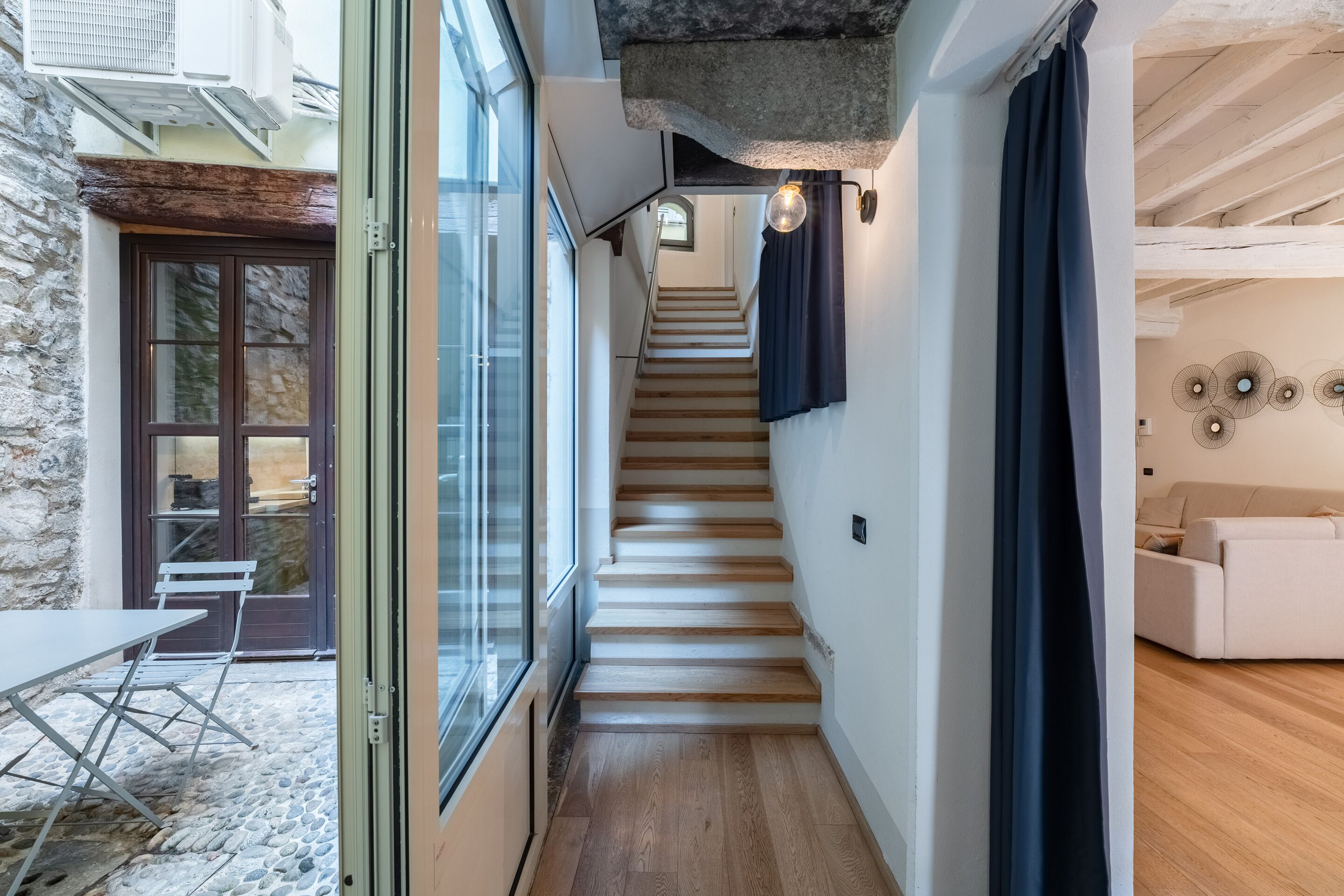 A staircase leading to a second floor with a stone wall on one side and a wooden floor.
