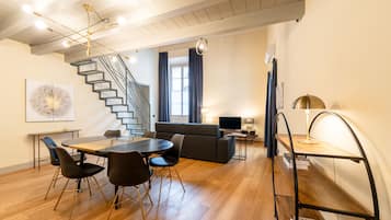 Un interno moderno con zona pranzo, una scala e un angolo relax con televisore.