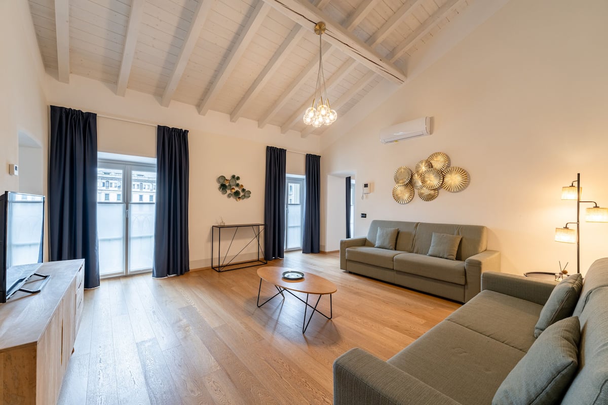 Un salon spacieux avec un plancher en bois, un canapé, une table basse et un téléviseur.