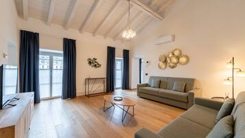 Amplia sala de estar con piso de madera, un sofá, una mesa de centro y un televisor.