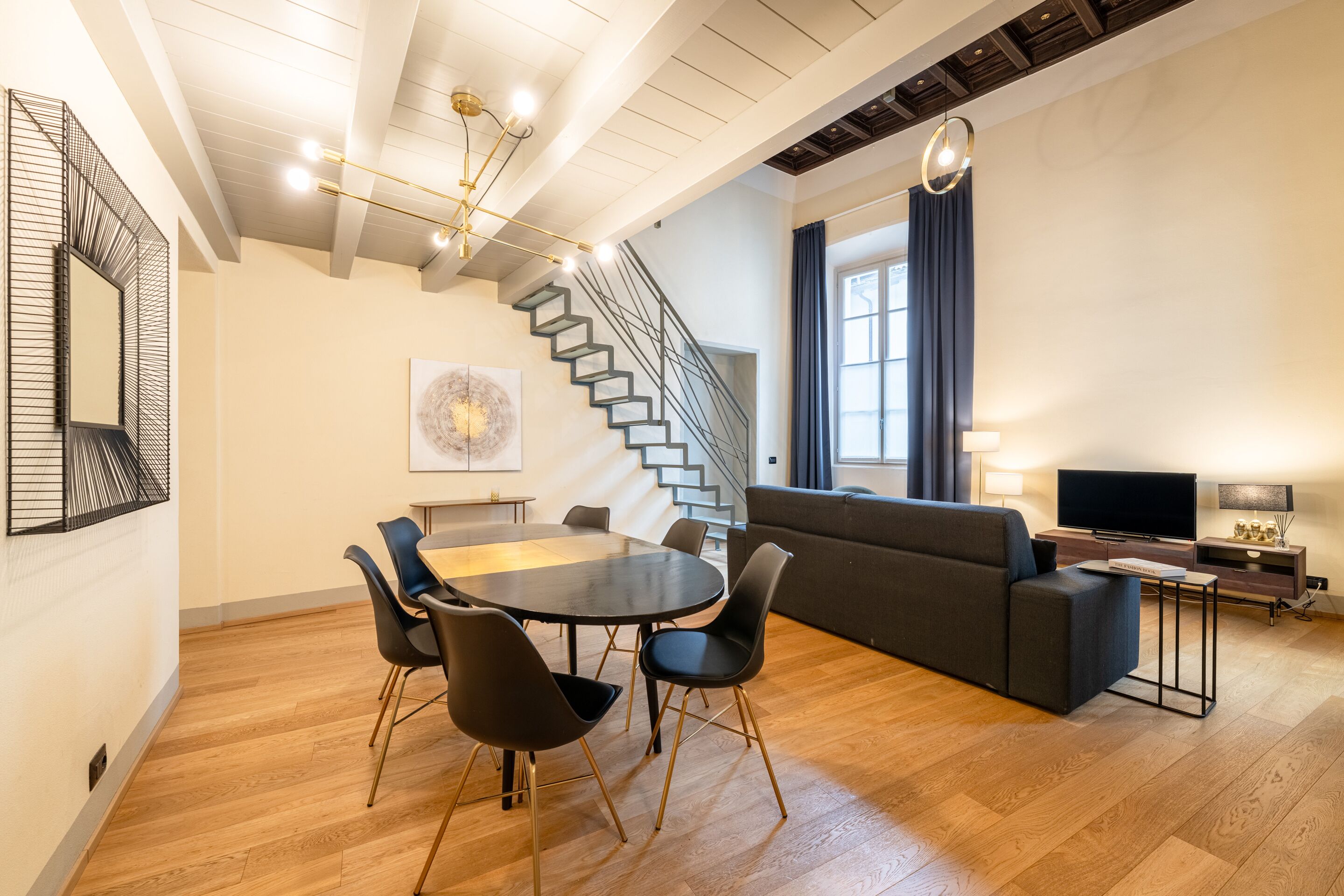 A modern living room with a staircase, a dining area, and a TV.