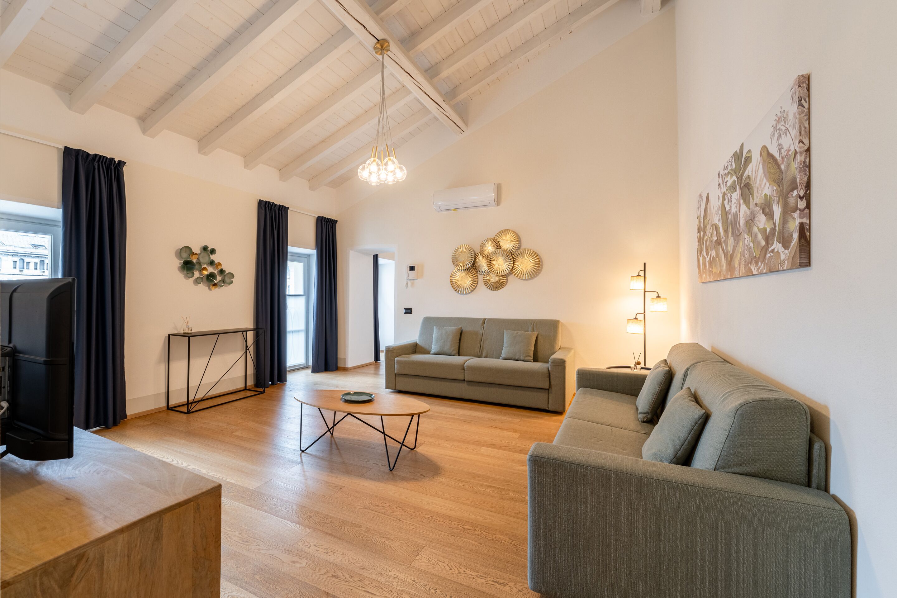 A spacious living area with a wooden floor, a sofa, a coffee table, and a television.