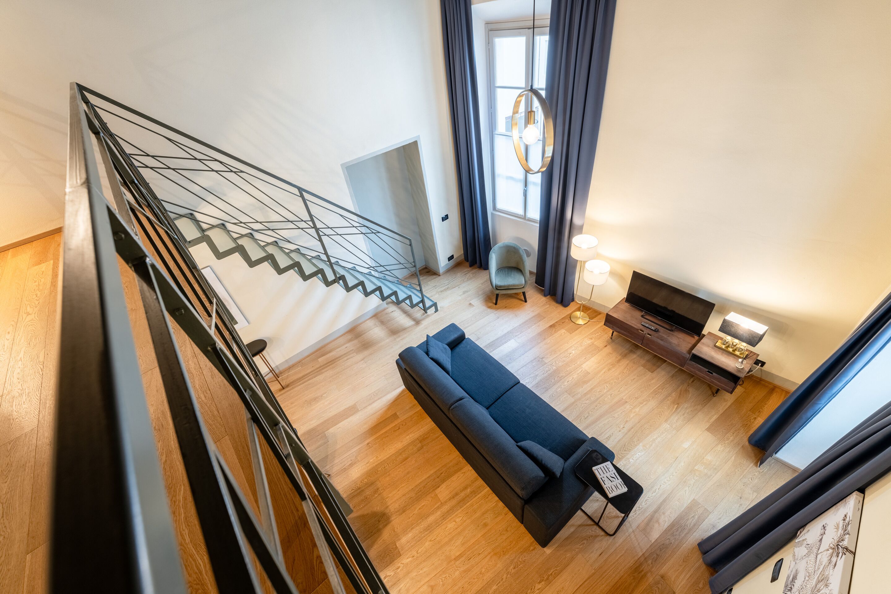 Un salon moderne avec un escalier, un canapé, un téléviseur et une console.