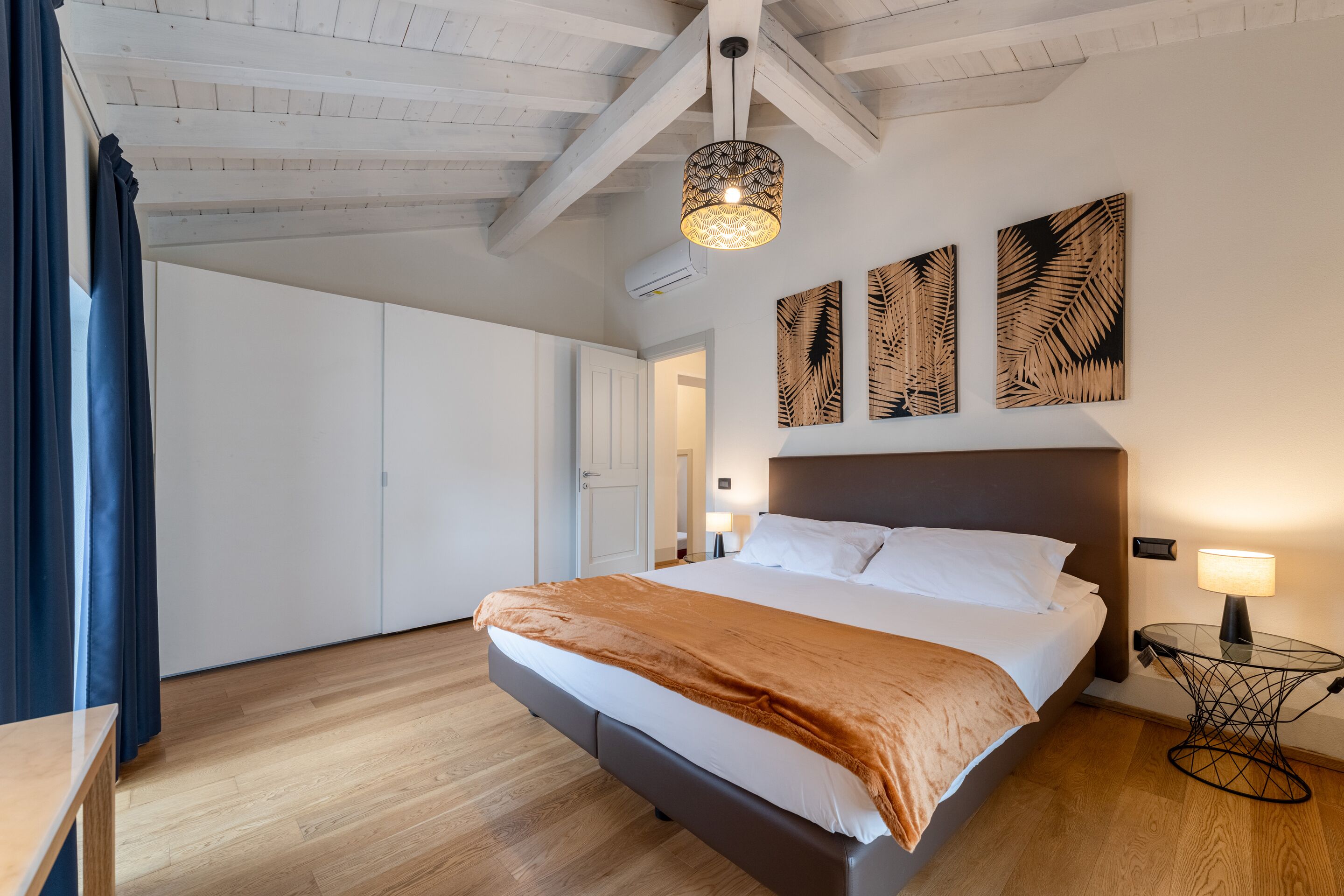 A bedroom with a bed, a bedside table, a lamp, and wall art.