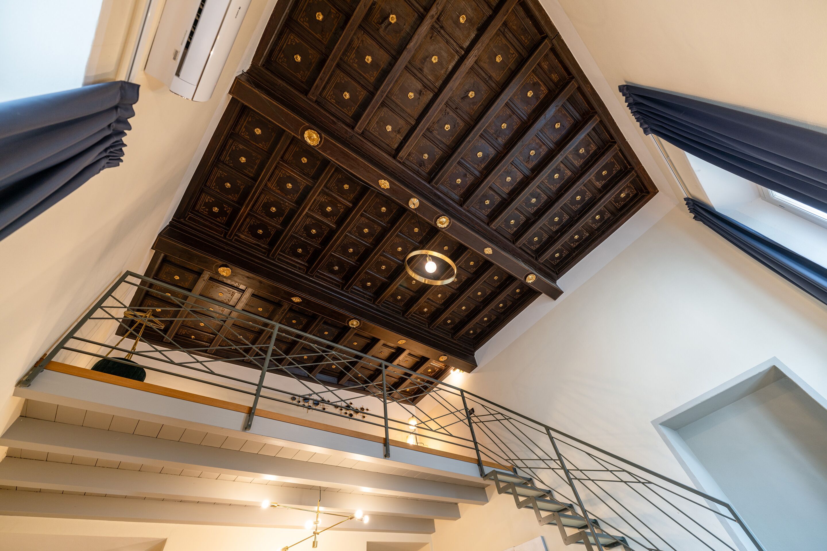 A multi-level interior with a wooden ceiling, a staircase, and a modern railing system.