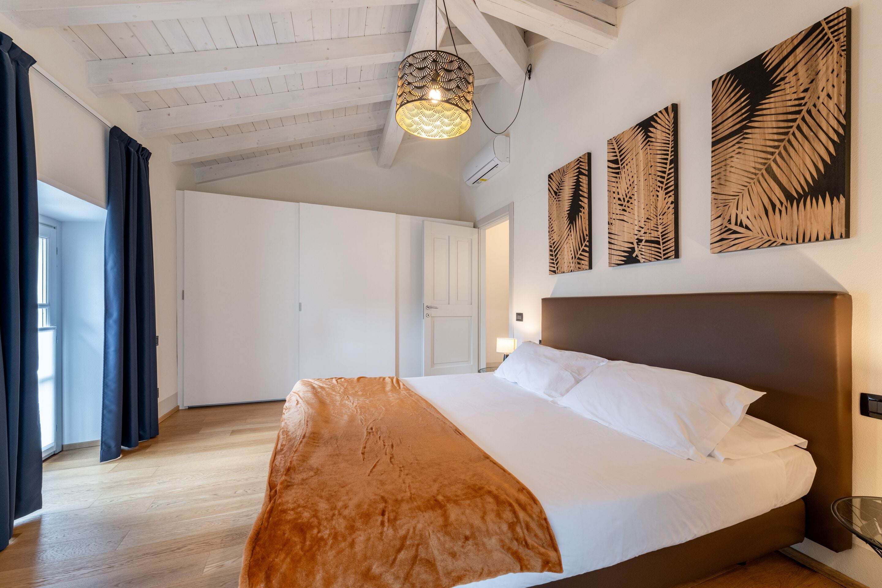 Un dormitorio con una cama grande, una lámpara colgante y decoración en la pared.